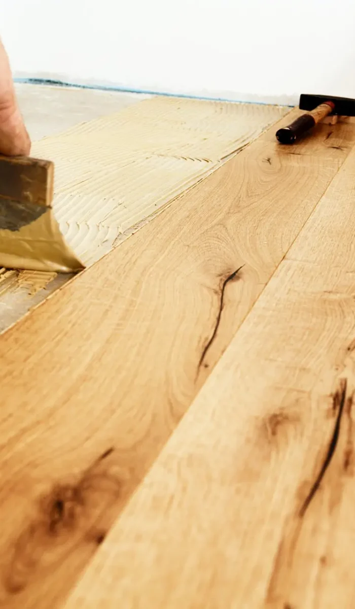 Man applying glue for laying finished parquet flooring, close-up